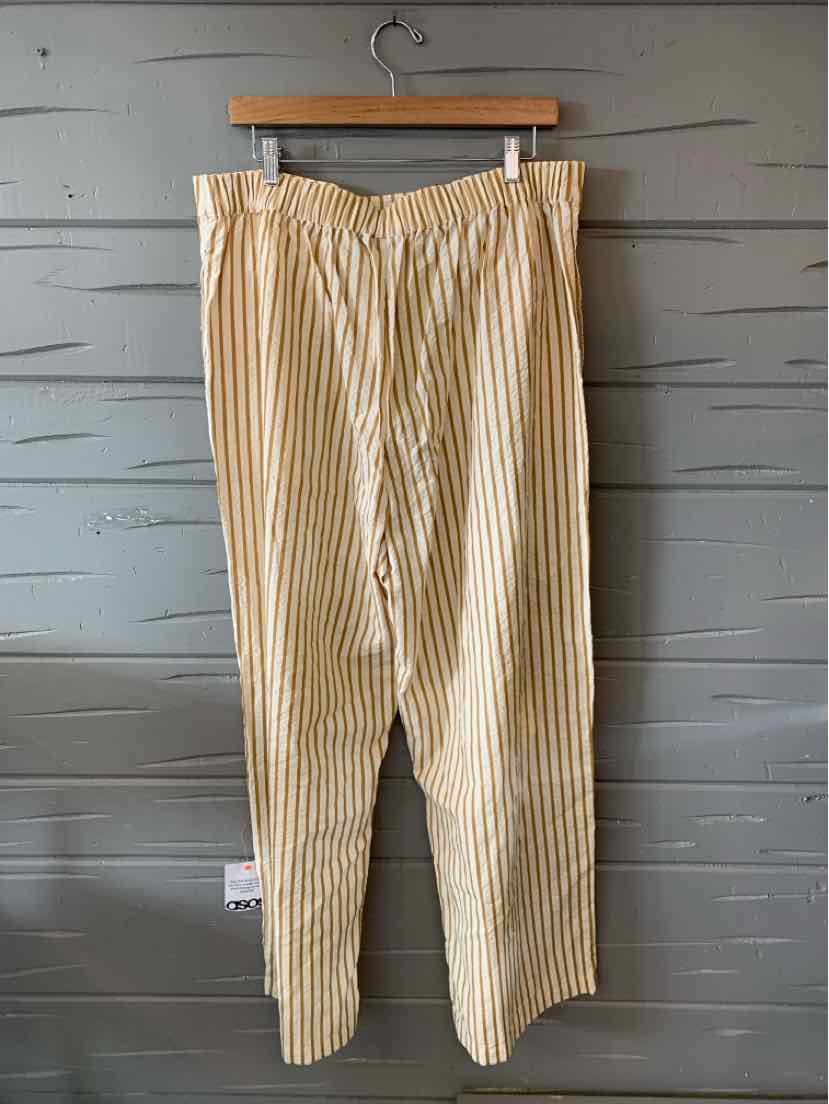 Beige and white vertical striped loose-fit trousers with an elastic waistband hanging on a wooden hanger.