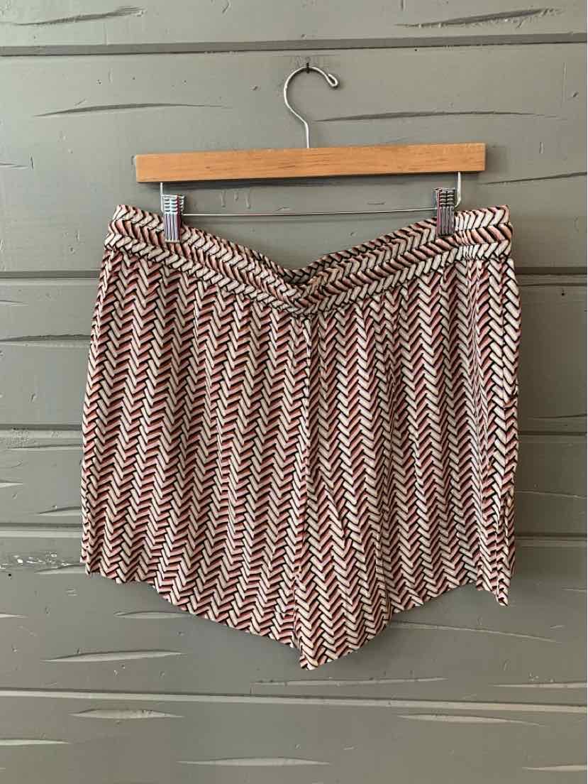 Mauve chevron-patterned shorts with gathered waistband hanging on wooden hanger against gray wall.
