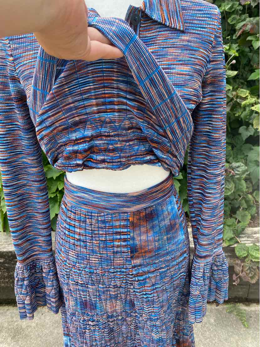 Space-dyed blue and orange long-sleeve cropped top with collared neckline and matching ruched mini skirt.