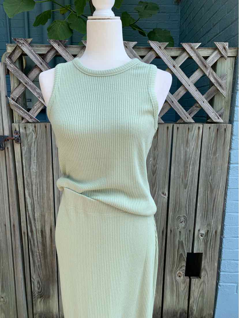 Light green sleeveless ribbed knit top and matching skirt set on a mannequin against a wooden fence background.