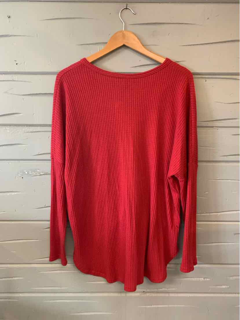 Red long-sleeve crew neck sweater with soft knit fabric hanging on wooden hanger.