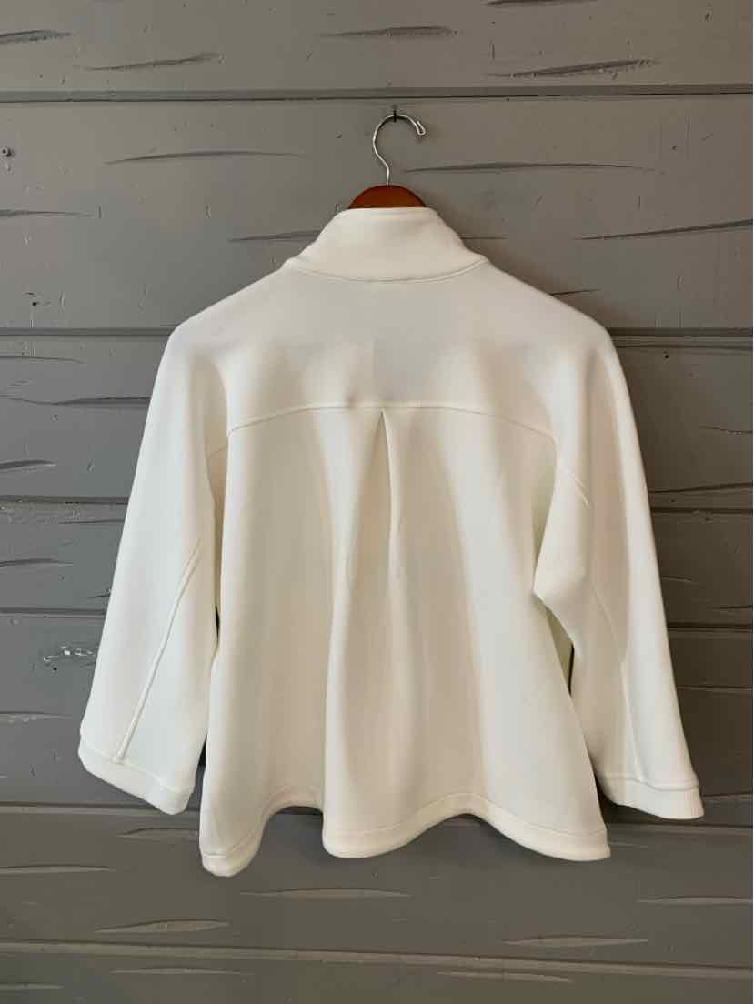 White long-sleeve blouse with buttoned cuffs and pleated back detail hanging on wooden hanger.