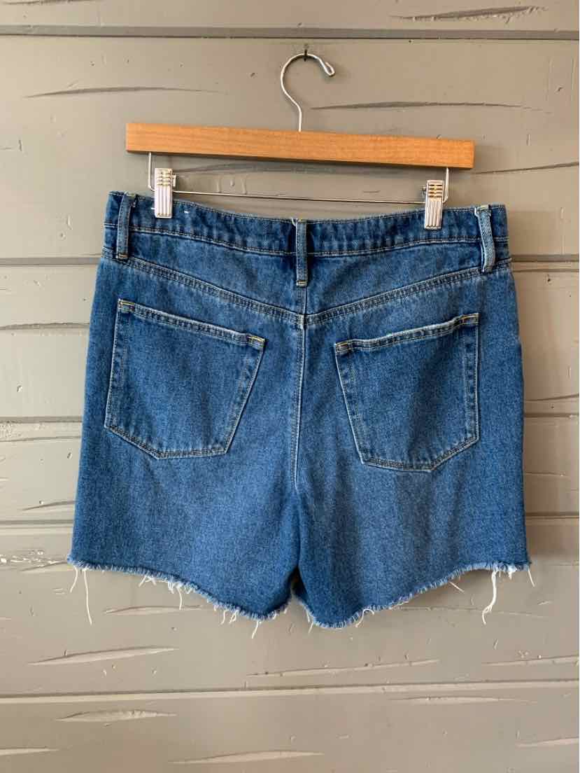 Blue denim shorts with frayed hems and two back pockets hanging on wooden hanger.
