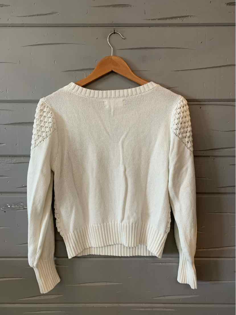 White knit sweater with textured shoulder details and ribbed cuffs and hem.