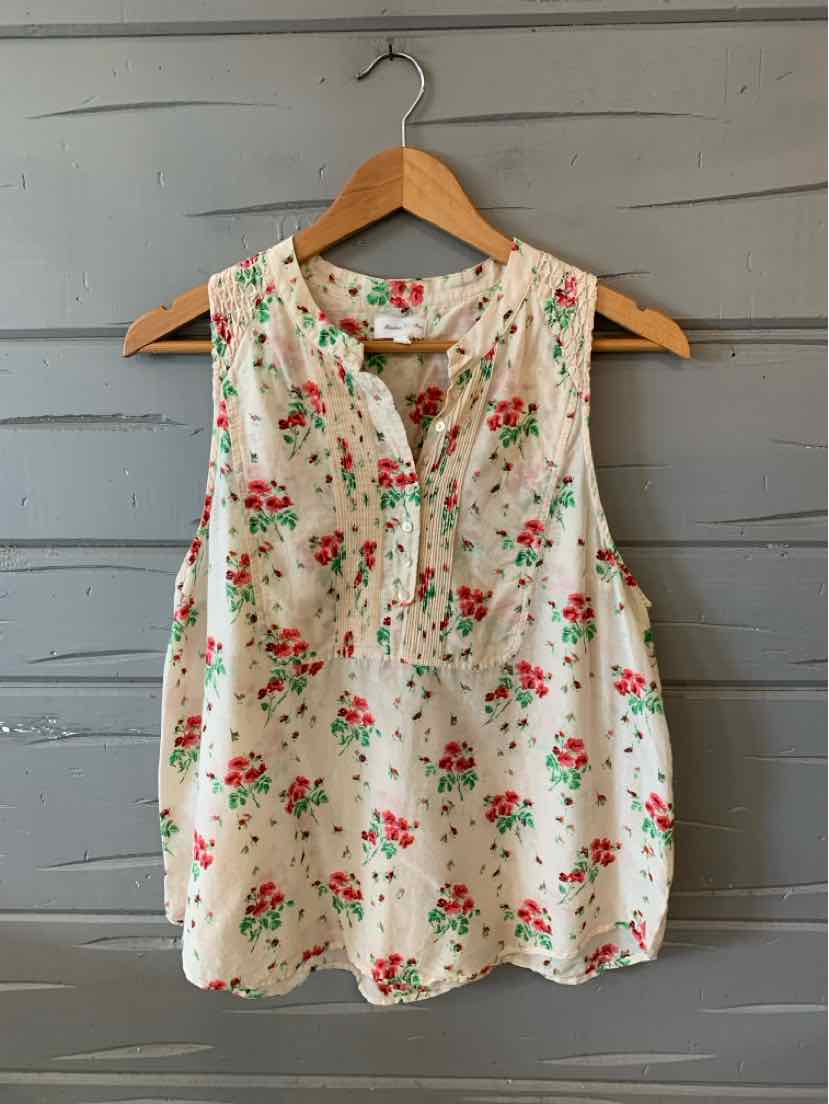 White sleeveless blouse with red and green floral print, round neckline, and buttoned placket.