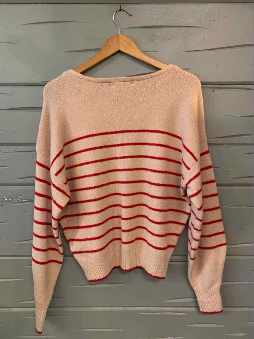 Beige knit sweater with red horizontal stripes and long sleeves on wooden hanger.