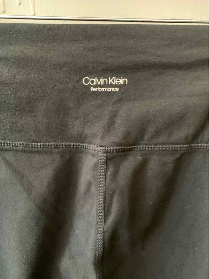 Black Calvin Klein Performance leggings with flatlock seams and white logo on back waistband.