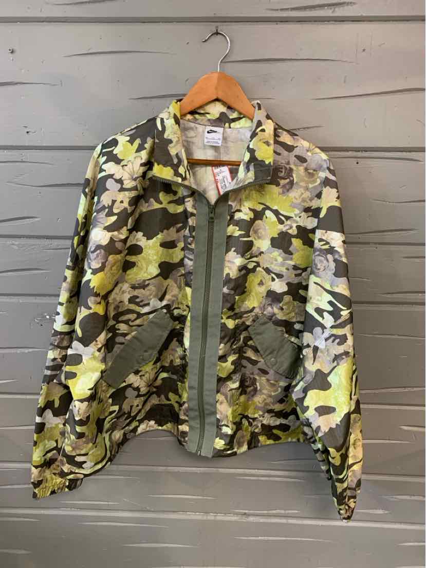 Women's oversized camo jacket in green and beige with button closure and large front pockets.