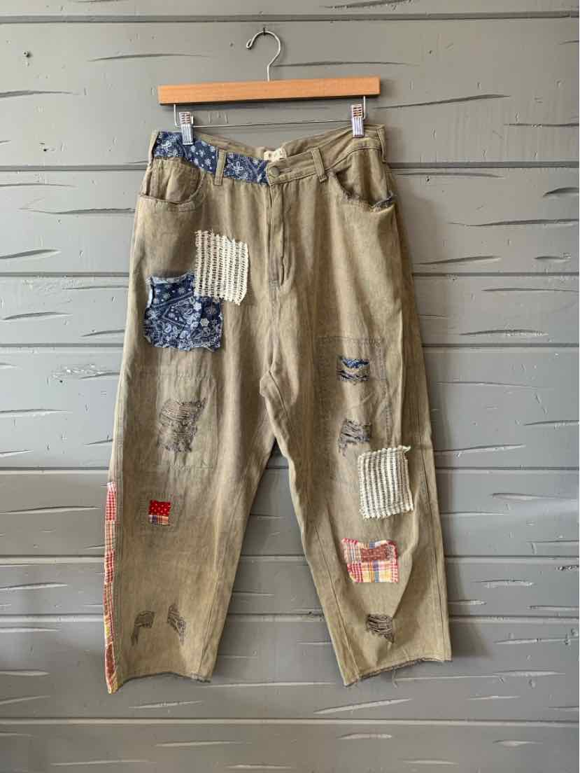 Beige patchwork pants with blue, white, and red fabric patches, relaxed fit, and elastic waistband.