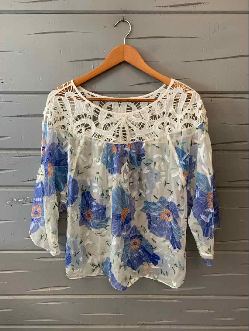 White blouse with blue floral print, sheer fabric, and intricate crochet lace yoke and shoulders, size 10.