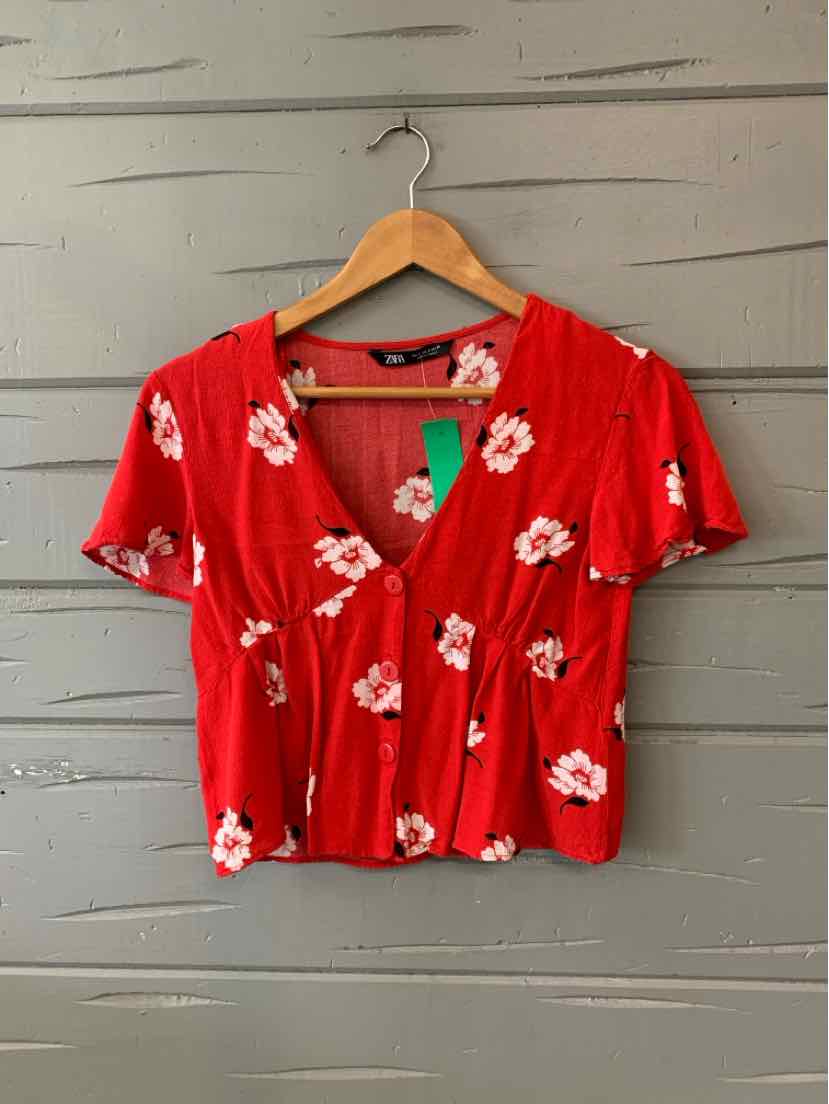 Red short-sleeve cropped blouse with white floral print and ruched front detail.