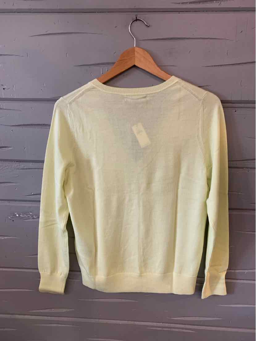 Light yellow long-sleeve sweater with crew neck, ribbed cuffs and hem, hanging on wooden hanger.