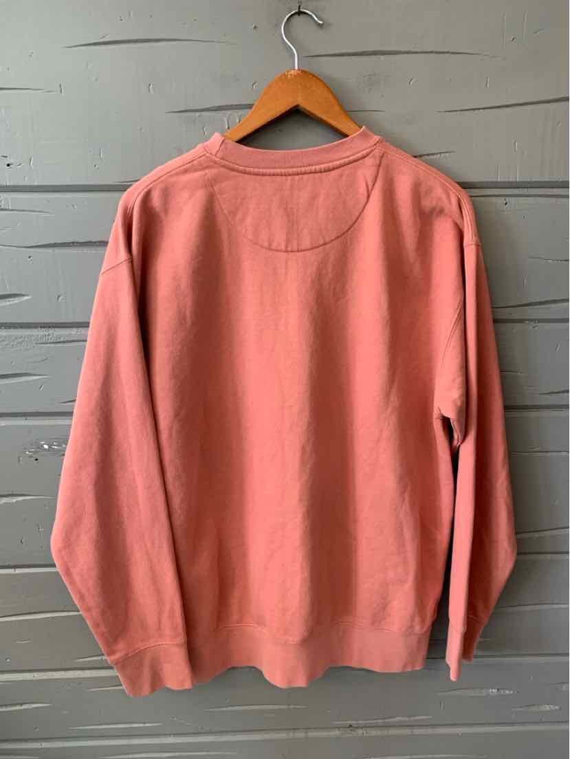Dusty pink long-sleeve crewneck sweatshirt with relaxed fit, hanging on wooden hanger.