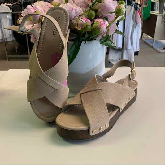 Taupe suede sandals with crisscross straps, adjustable ankle strap, and gold-tone studs on brown sole.