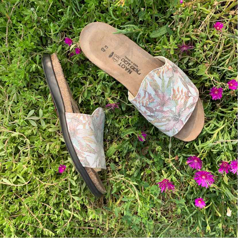 Beige slide sandals with pink and green floral print fabric straps and cushioned brown footbeds.