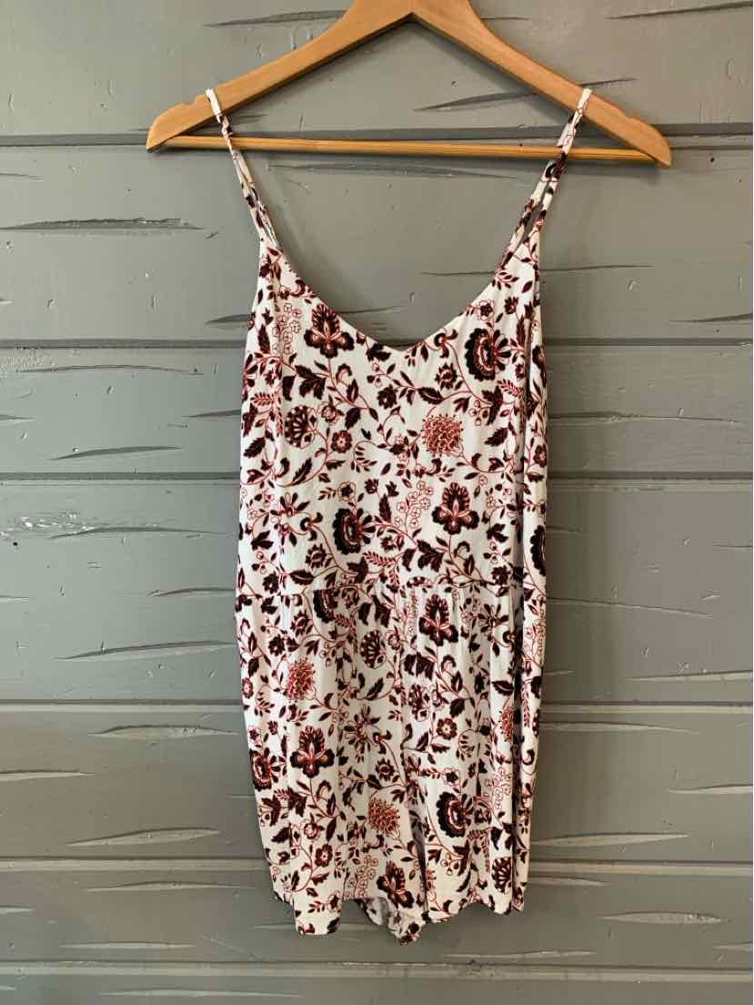 White floral sleeveless mini dress with thin spaghetti straps on wooden hanger.