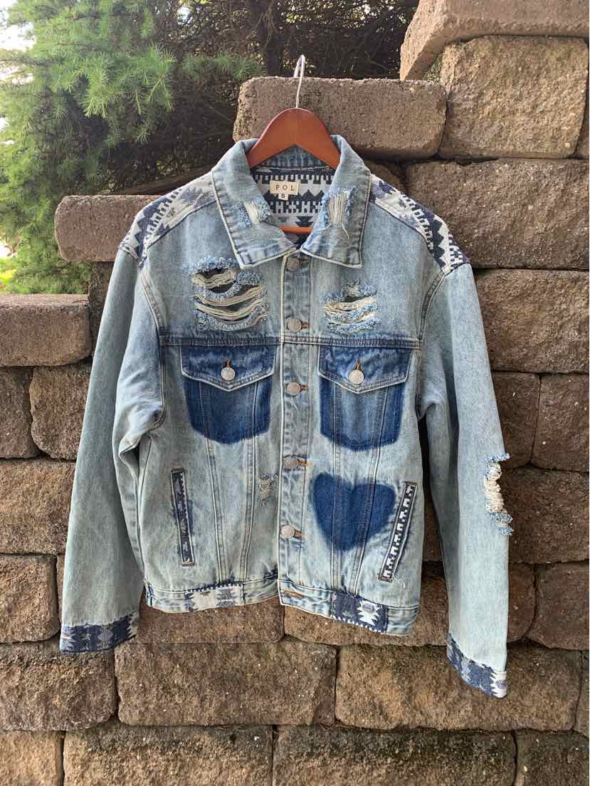 Light blue distressed denim jacket with heart-shaped dark blue front pockets and studded detailing on front and shoulders.
