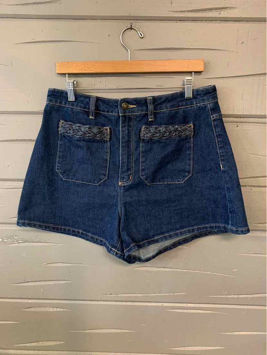 High-waisted dark blue denim shorts with front pockets and braided trim detail on pocket edges.