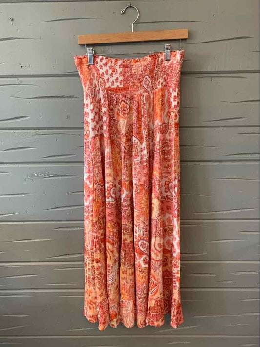 Pink floral patterned maxi skirt with pleats and a flowy silhouette hanging on wooden hanger.
