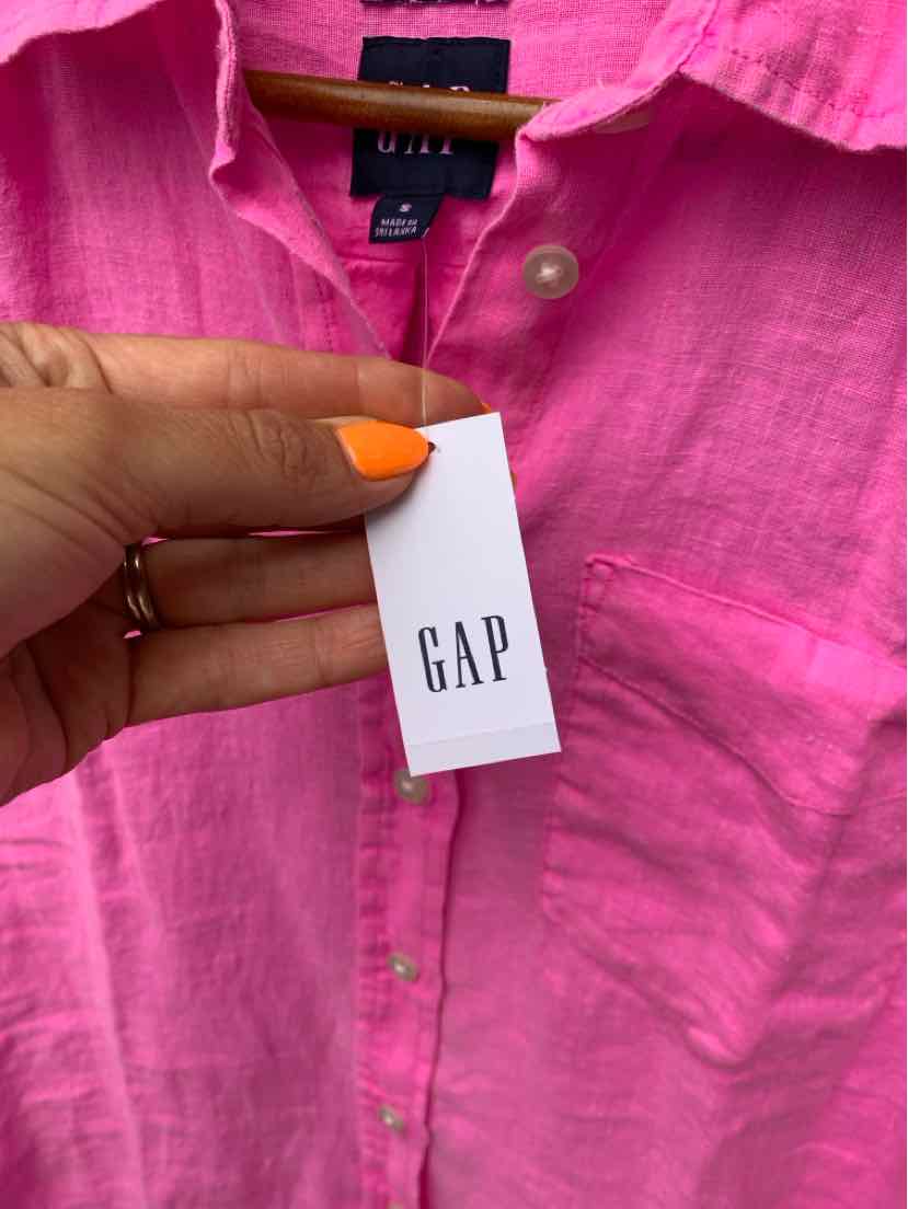 Bright pink linen button-up shirt with crisp collar and white GAP tag held by hand with orange nail polish.