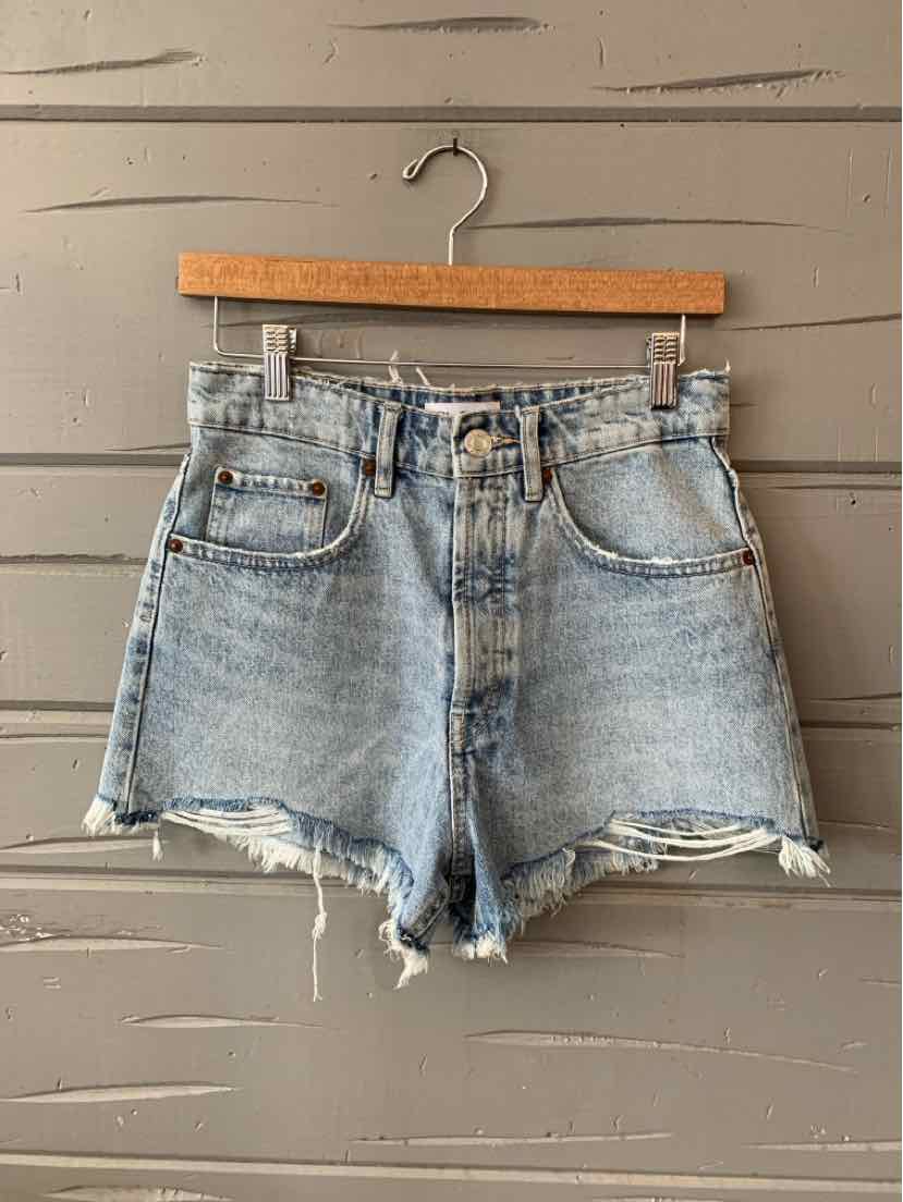 Light blue high-waist denim shorts with frayed hems and classic five-pocket design hanging on wooden hanger.