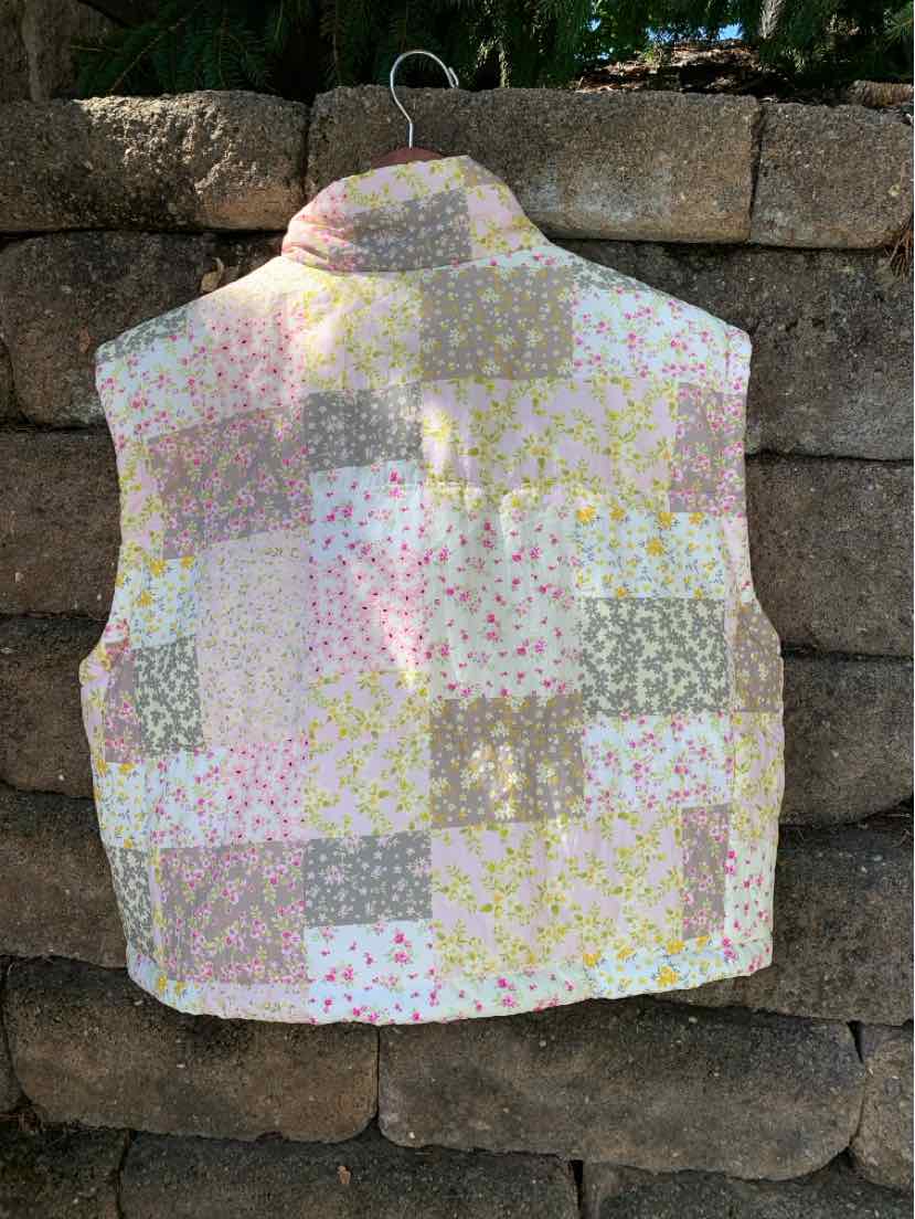 Pink floral patchwork sleeveless vest with high collar and quilted texture.