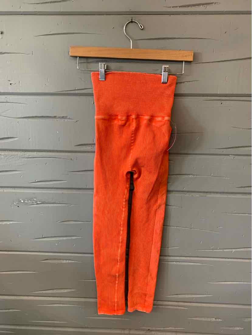 High-waisted orange ribbed leggings with a wide waistband in size XXS hanging on a wooden hanger.