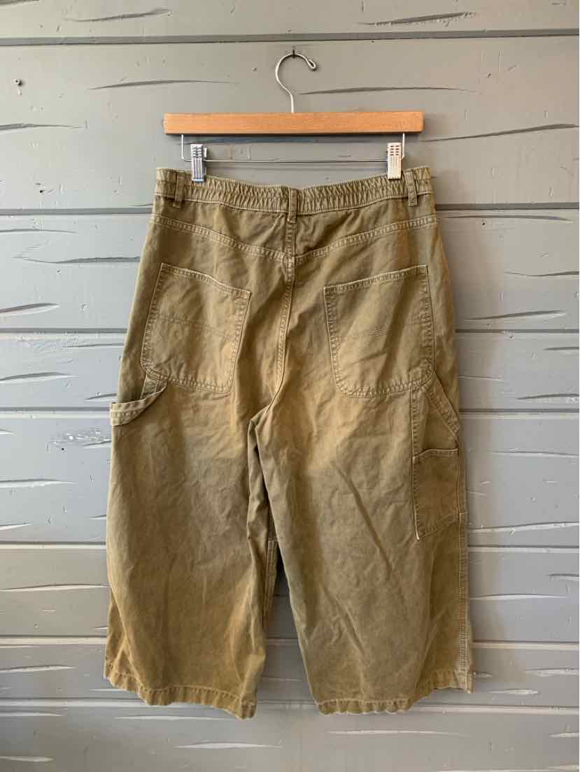 Olive drab cargo pants with a relaxed fit, elastic waistband, and large side pockets hanging on a wooden hanger.