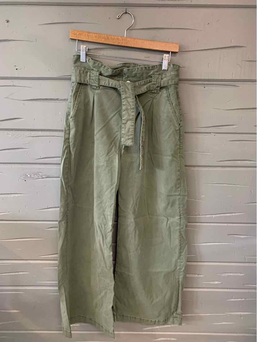 Olive green high-waist wide-leg pants with fabric belt and front pockets hanging on wooden hanger.