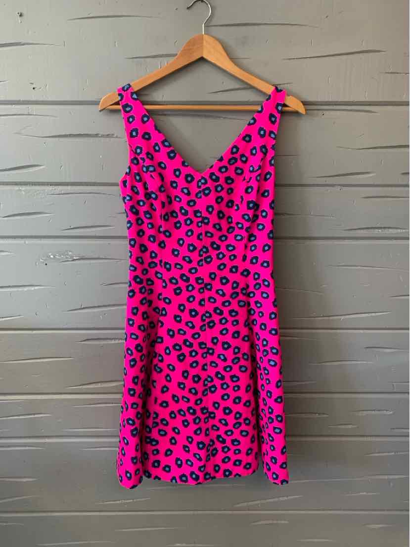 Pink sleeveless dress with black cheetah print, V-neck and fitted waist on wooden hanger.