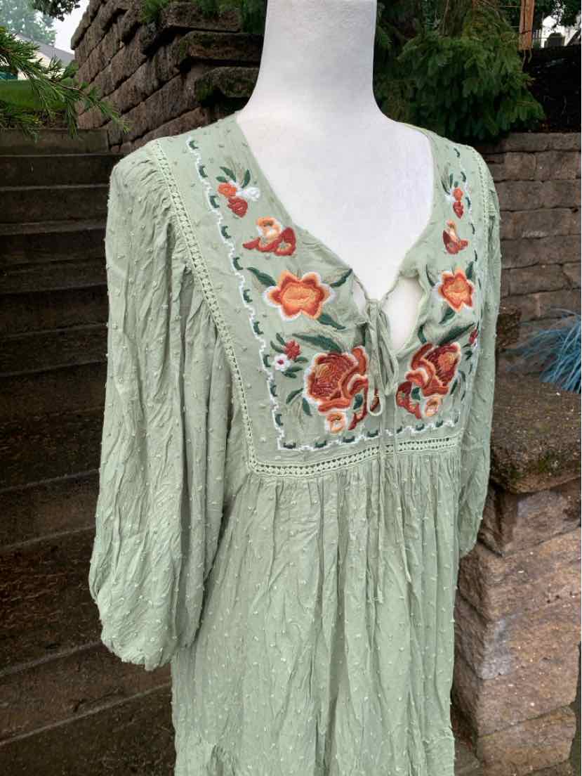 Light green long-sleeve dress with floral embroidery and scalloped neckline detailing.