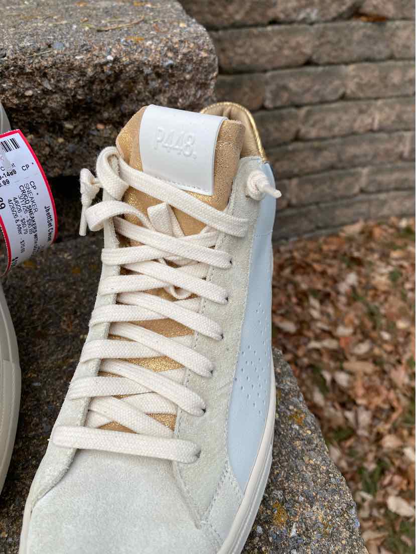 White high-top sneaker with off-white suede panels, white laces, and embossed logo on tongue.