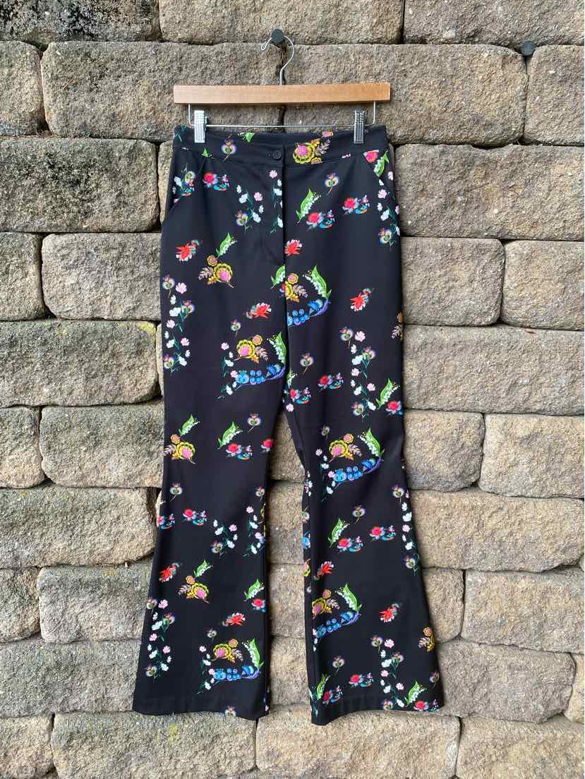 Black flared pants with vibrant multicolor floral pattern and high waist.
