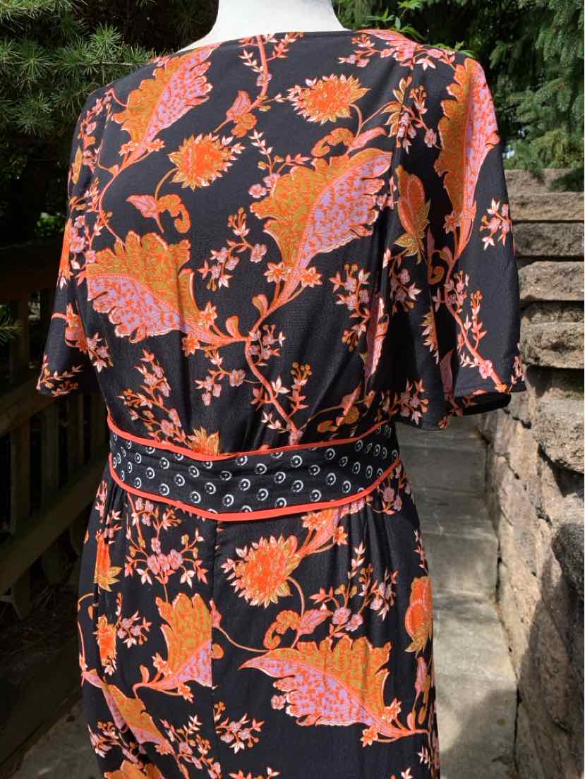 Black dress with orange floral print, short sleeves, and a belted waist with patterned details.