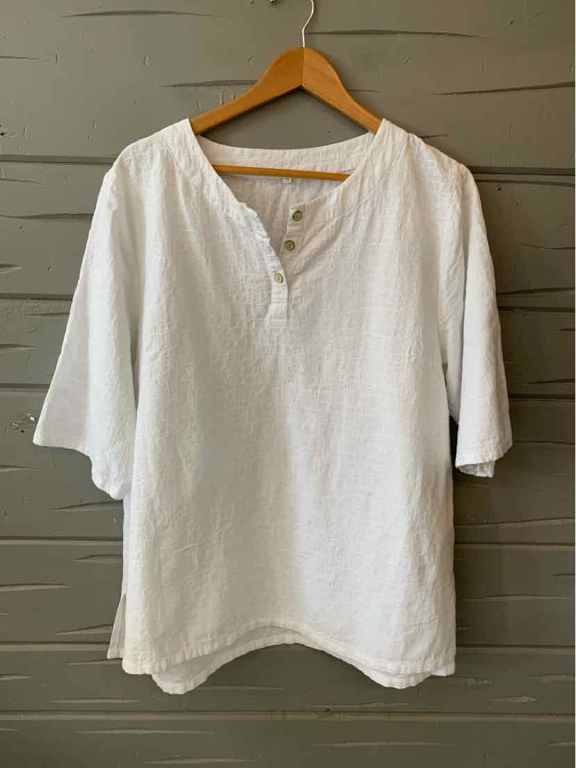 White oversized linen shirt with three-quarter sleeves and a round neckline with a short button placket.