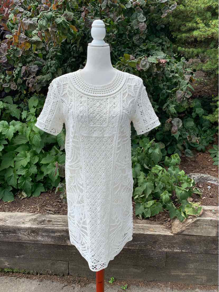 White lace short-sleeve dress with round neckline and floral crochet pattern.