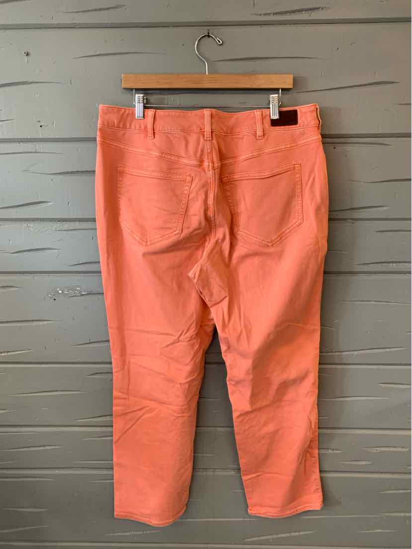 Coral orange high-waist pants with back pockets and button closure hanging on wooden hanger.