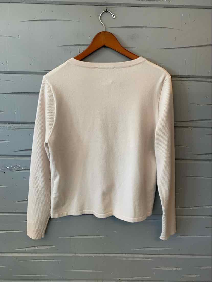 Cream long-sleeve knit top with a slightly loose fit and round neckline hanging on wooden hanger.