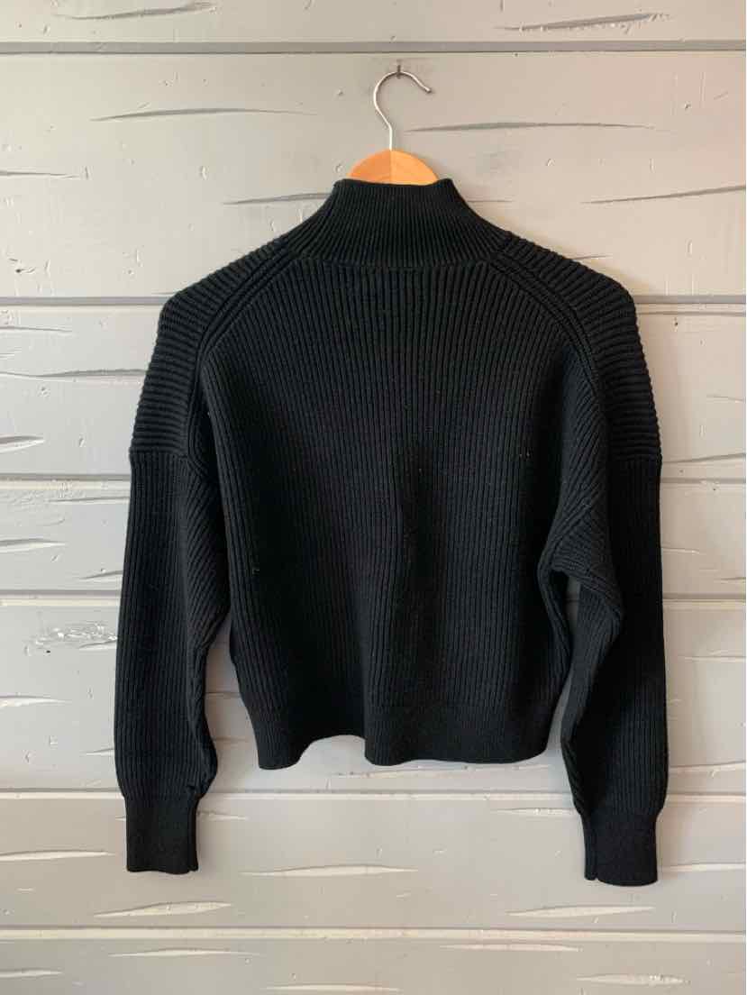 Black long-sleeve knit sweater with ribbed cuffs and hem, medium size, hanging on wooden hanger.