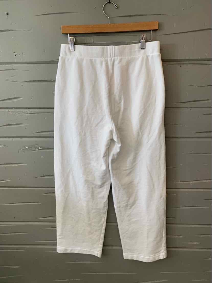 White high-waist pants with a straight-leg cut and an elastic waistband hanging on wooden hanger.