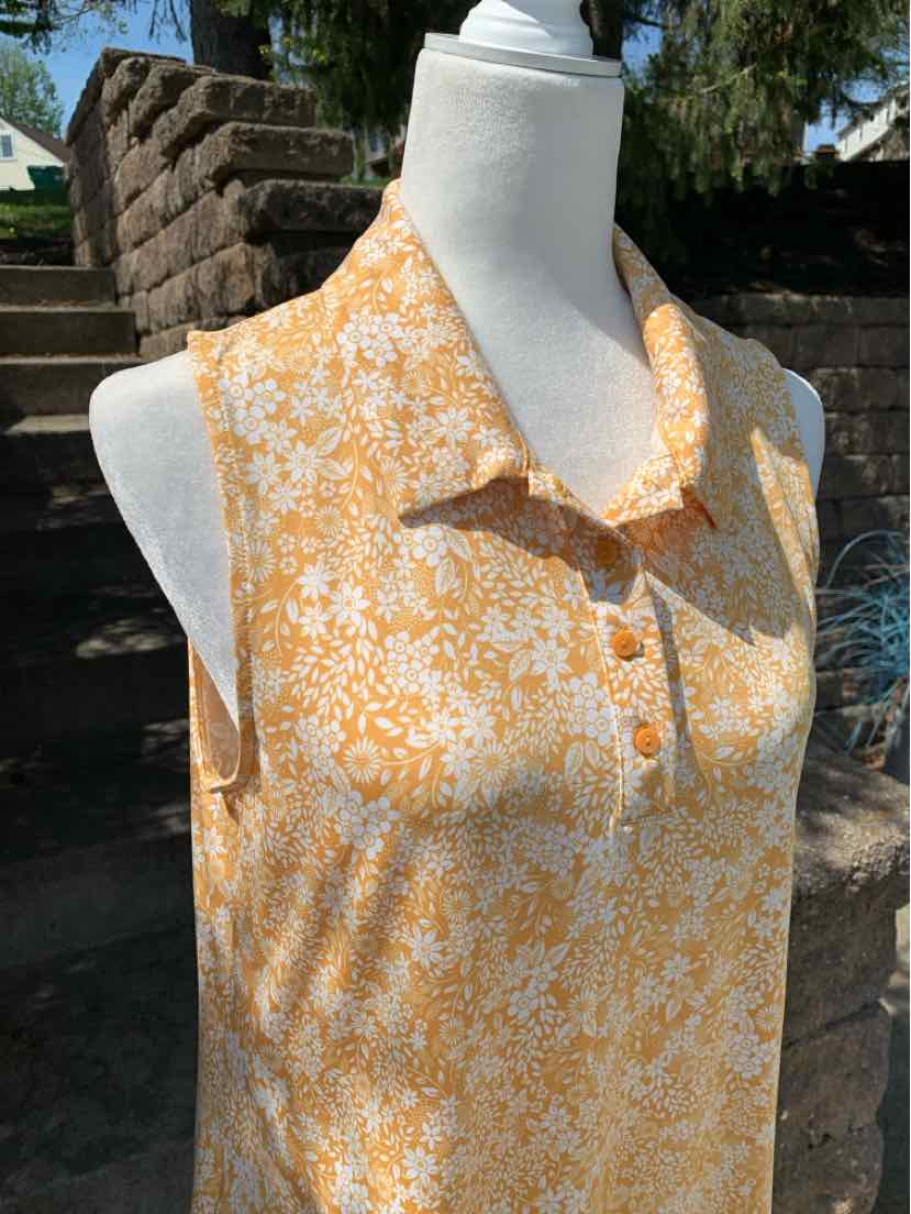 Sleeveless yellow floral blouse with small collar and button placket, lightweight fabric.