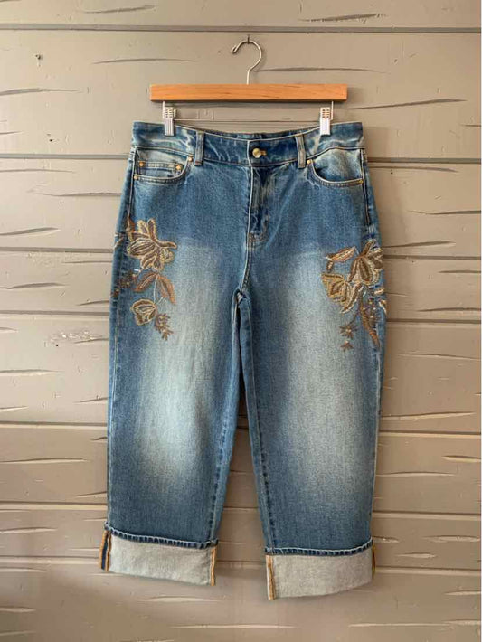 Blue denim capri jeans with floral embroidery on thighs and cuffed hems.