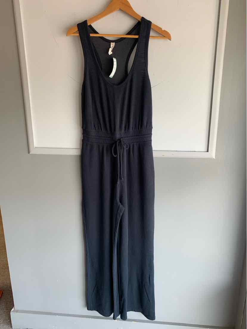 Sleeveless dark gray jumpsuit with scoop neckline and cinched waist, hanging on wooden hanger.