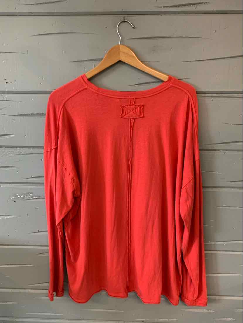 Long-sleeve solid red shirt with relaxed fit and crew neckline hanging on wooden hanger.