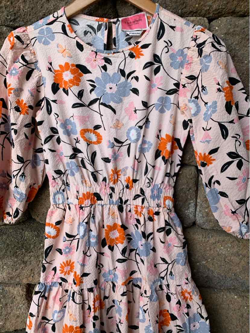 Pink floral dress with puff sleeves and elastic waist in size XS hanging on wooden hanger.