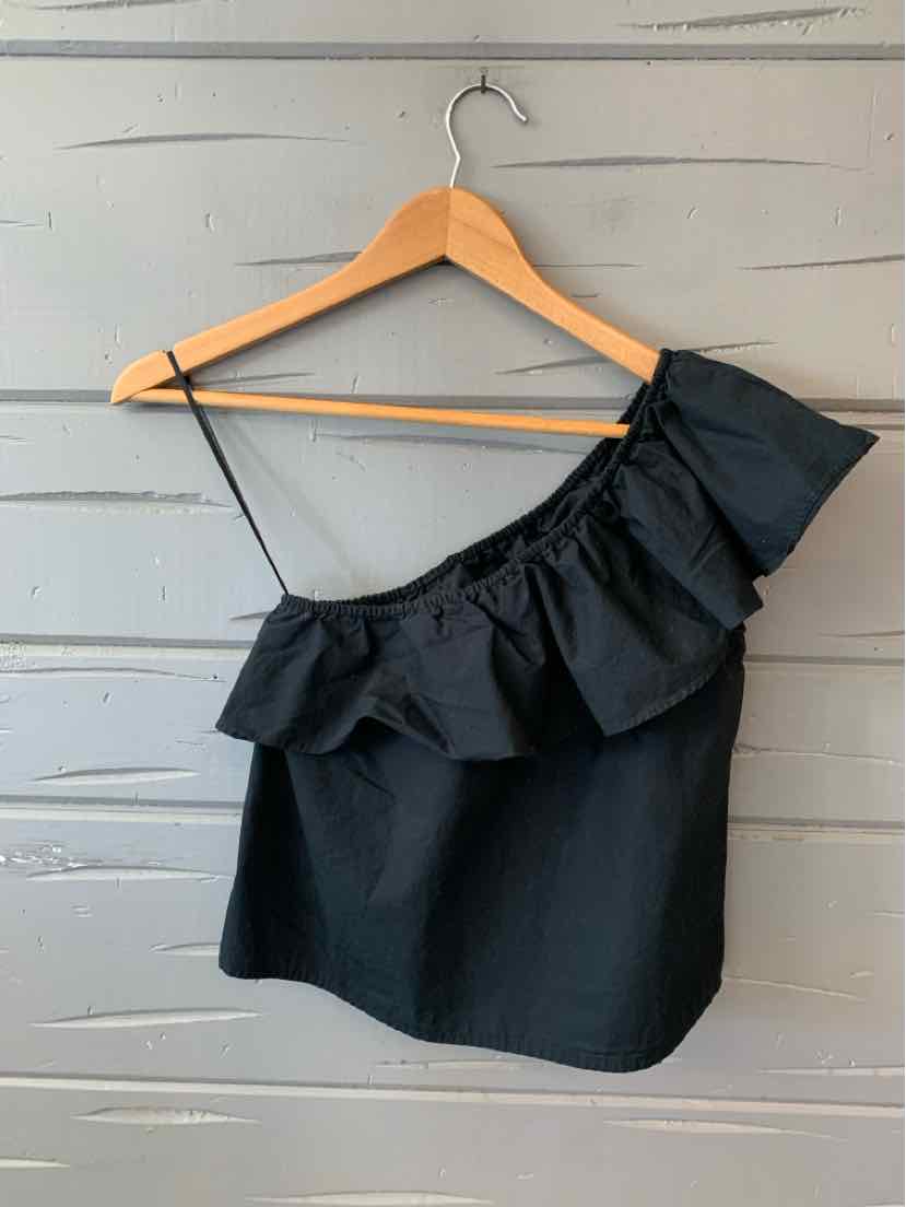 Black one-shoulder top with ruffle detail on wooden hanger against gray wooden background.