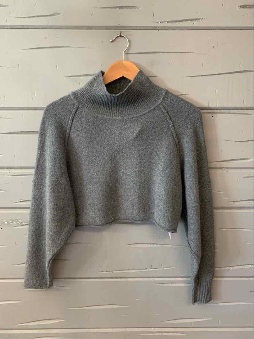 Gray cropped sweater with long sleeves and mock neck, soft knit fabric on wooden hanger.