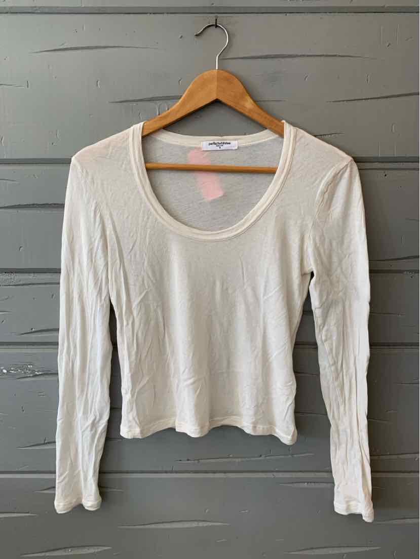 White long-sleeve fitted shirt with scoop neckline on wooden hanger against gray wall.