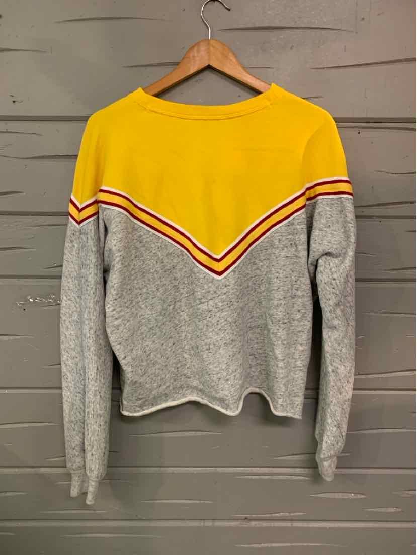 Long-sleeve knit sweater with yellow upper chest and shoulders, gray lower body and sleeves, and red and white chevron.