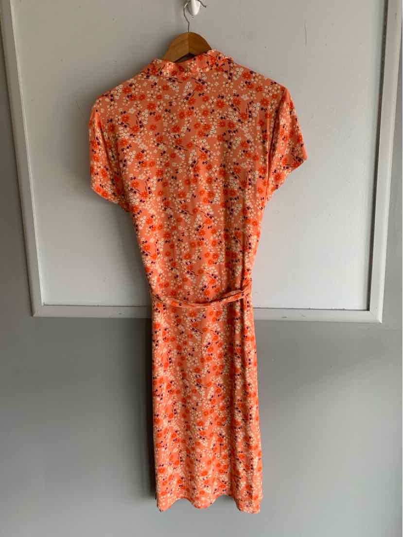 Orange floral midi dress with short sleeves and belted waist on wooden hanger.